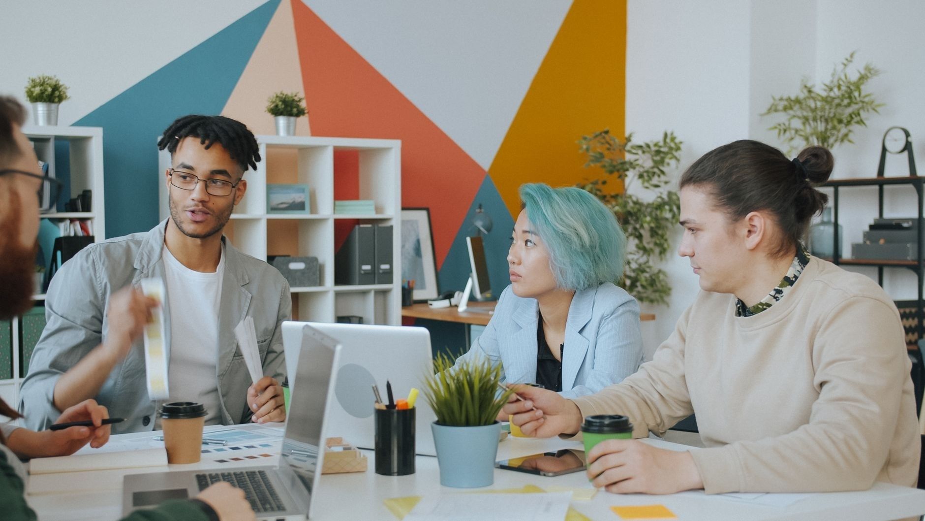 Kreativt team diskuterar briefen runt ett bord med datorer och skisser