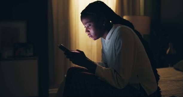 Person sitter i mörker och tittar på sin smartphone
